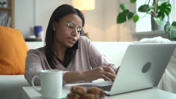 African Woman with Glasses at Home Working at Computer and Talking on Phone Spbd