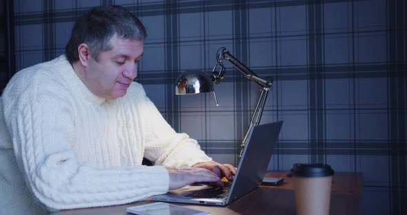 A Middleaged Man Works in Front of a Computer Late at Night