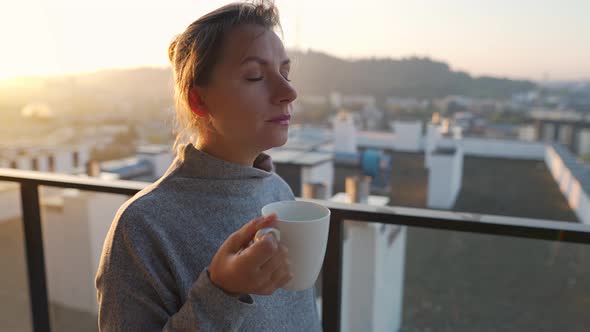 Woman Starts Her Day with a Cup of Tea or Coffee on the Balcony at Dawn