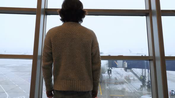 Passenger Comes to Window to Look at airplane at Airport