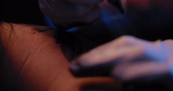 Close up of tattoo artist's hand making a tattoo drawing on a person's back