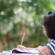 Little Asian girl doing homework in the garden. - VideoHive Item for Sale