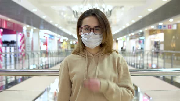Young Woman in Medical Mask at the Mall. The Masked Woman Protects Herself From the Epidemic of the