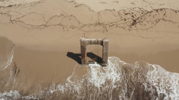 Aerial View of old broken pier made of cement in the middle of the ocean near Santa Cruz California.