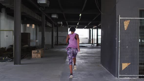 African american woman wearing sports clothing jogging through an empty urban building