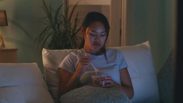 Asian Mother Having Dinner in Front of TV