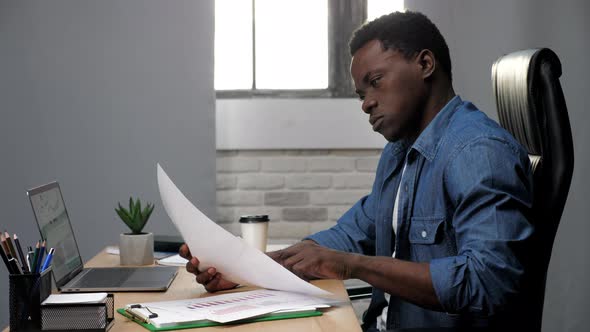 Thoughtful African American Businessman Looks Business Report in Office