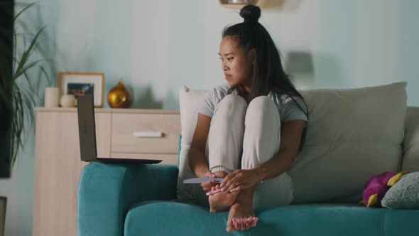 Asian Female Doing Pedicure Near Laptop