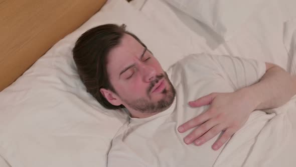 Casual Young Man Coughing While Sleeping in Bed