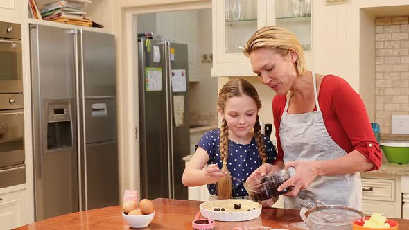 Playful mother and daughter putting berries over dough 4K 4k