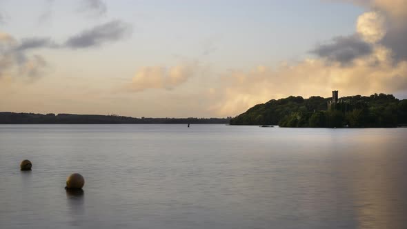 Time lapse of a castle ruin on lake horizon during sunset evening in Ireland.