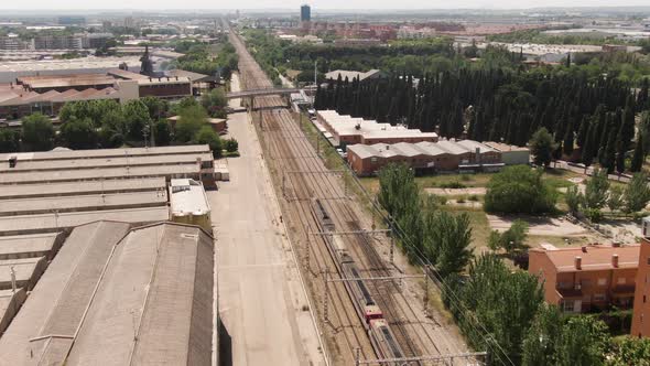 Passenger train driving through suburbs of Madrid, aerial drone view