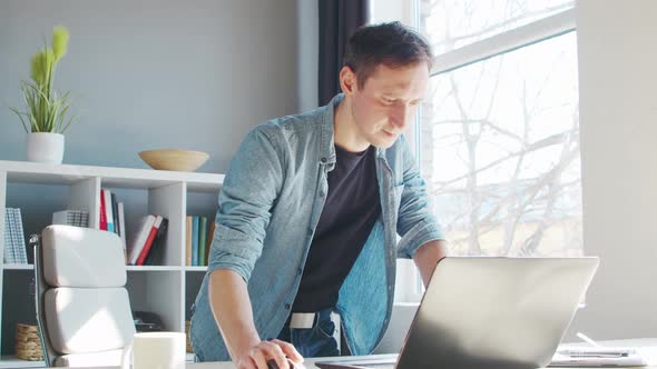 Young male entrepreneur works at home office at the computer.