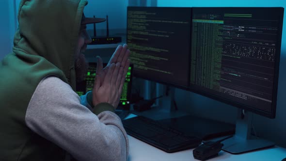 Excited Hacker in Mask Rubs His Hands Before Attempting to Hack or Infects System with a Virus