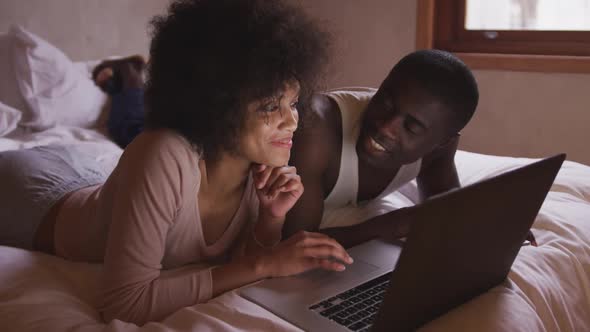 Couple using computer in bedroom at home