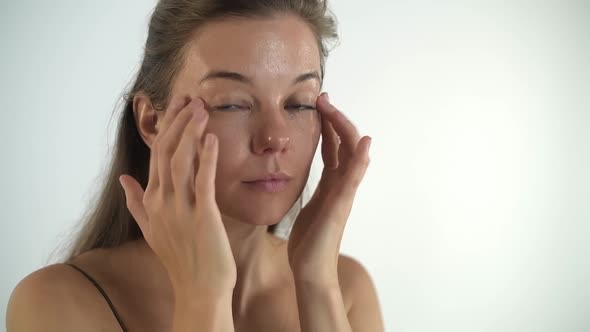 A Young Beautiful Girl Applies Cream to Her Face