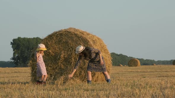 Woman with Daughter Having Fun Next to Hay Bale