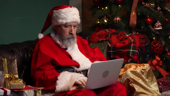 Santa Claus Orders Gifts on the Internet Using a Laptop