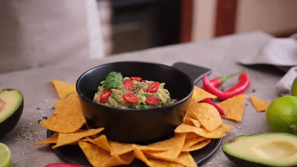 Woman Dips Nachos Chips to Freshly Made Guacamole Dip Sauce in Marble Bowl Mortar