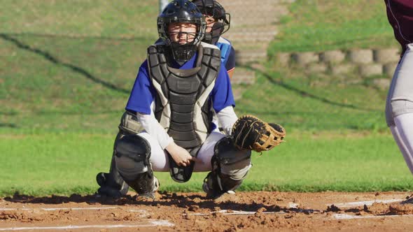 Caucasian female baseball player in catcher position catching ball on baseball field