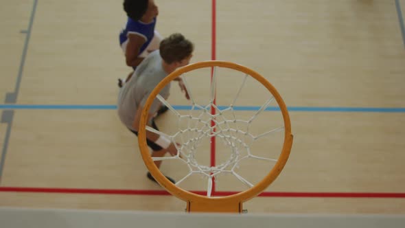 Overhead view of african american male basketball player scoring goal against diverse players