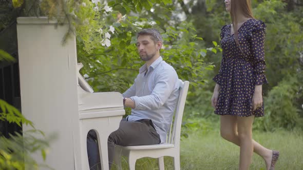 Side View of Absorbed Pianist Playing Musical Instrument Outdoors. Portrait of Confident Caucasian