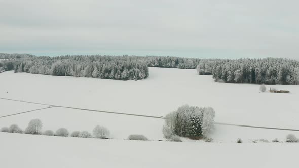 Aerial of white car driving through wonderful snow white landscape