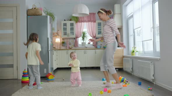 Woman Mother Plays With Two Children Girls Toys In The Room