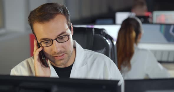 Scientist Working on Computer and Talking on Phone in Lab