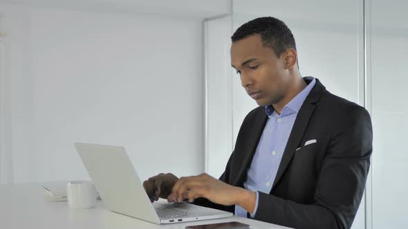Pensive Casual AfroAmerican Businessman Thinking and Working on Laptop