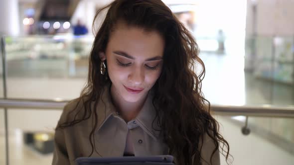 The Girl Looks at the Tablet and Looks at the Camera