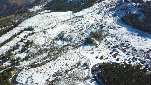 Aerial view of a road and the woods on a snowed mountain.