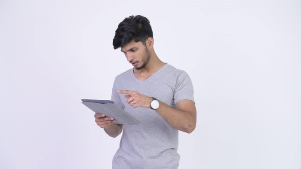 Young Stressed Bearded Indian Man Using Digital Tablet and Getting Bad News