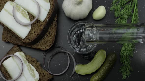 Pour Alcohol Drink Vodka From a Bottle in Shot Glass. Surface with Snacks