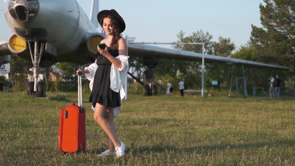 Young Woman with a Phone in Her Hands on the Background of the Plane