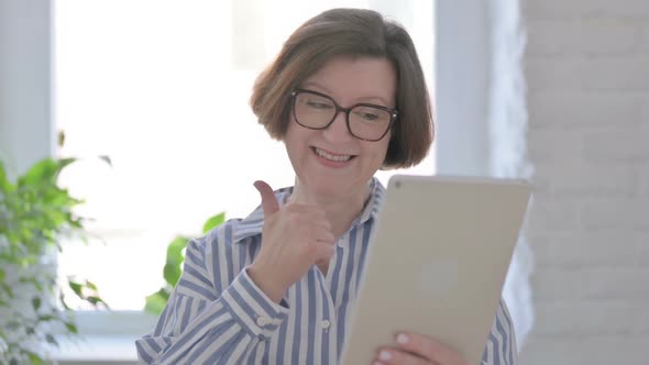 Portrait of Senior Woman Celebrating on Tablet in Office