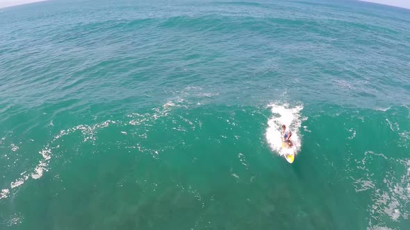 Aerial view of a man sup stand-up paddleboard surfing in Hawaii.