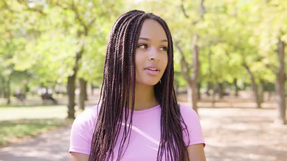 A Young Black Woman Smiles at the Camera in a Park on a Sunny Day - Closeup