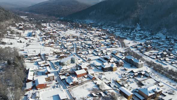 Settlement in the mountain saddle. A cinematic winter landscape. Drone footage