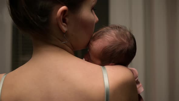 Newborn baby lies on the shoulder of his mother, close-up