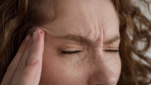 Extreme close up studio shot of young caucasian woman having migraine.