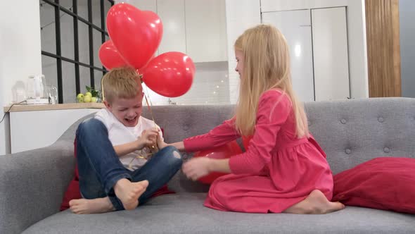 Little Boy and Girl Having Fun Playing with Red Heart Shape Balloons at Home