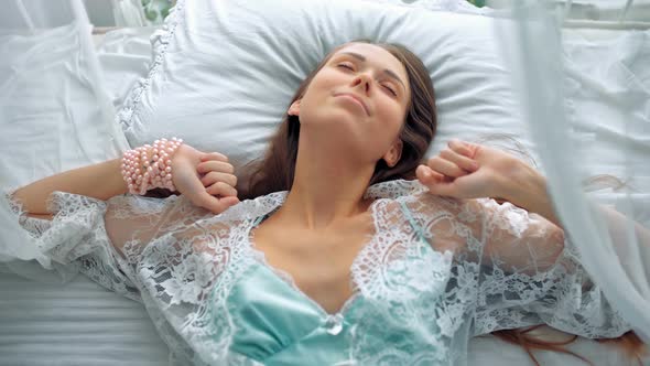 Beautiful Young Woman Waking Up in the Light White Room