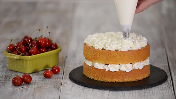Decorating a Cherry Cake with Cream From the Pastry Bag