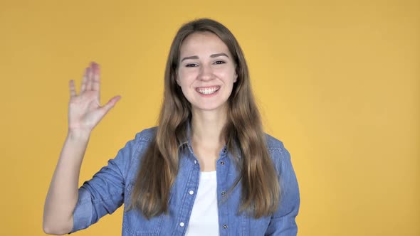 Pretty Woman Waving Hand to Welcome Isolated on Yellow Background