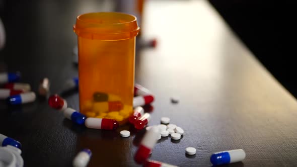 Slow motion prescription drug medication pills falling next to antibiotics and narcotics.