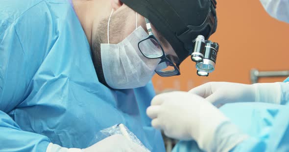 Closeup Face of Male Veterinarian in Glasses White Gloves Cap and in Surgical Outfit While He is