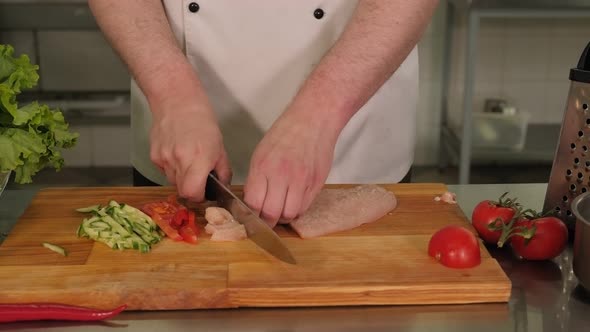 Closeup of the Chef Slicing Chicken Meat and Vegetables on a Cutting Board