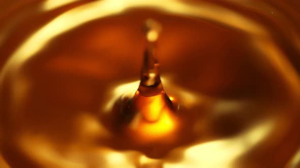 Super Slow Motion Shot of Droplet Falling Into Golden Liquid at 1000Fps.