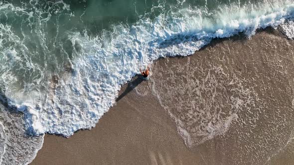 A young girl happily fights with the waves aerial view 4 K